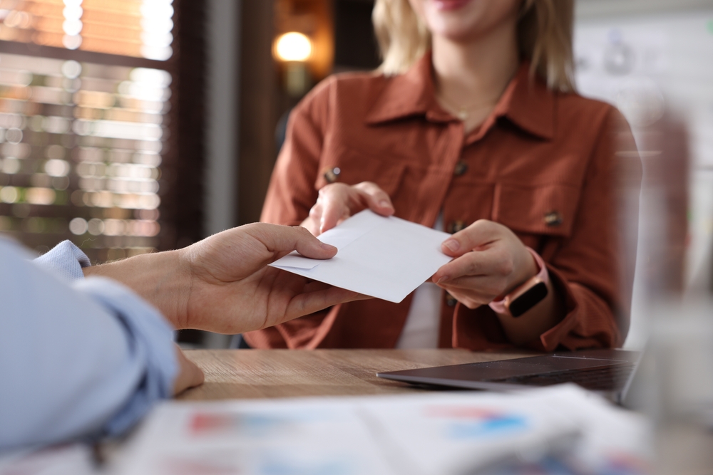 Woman handing an envelope to a man across a desk