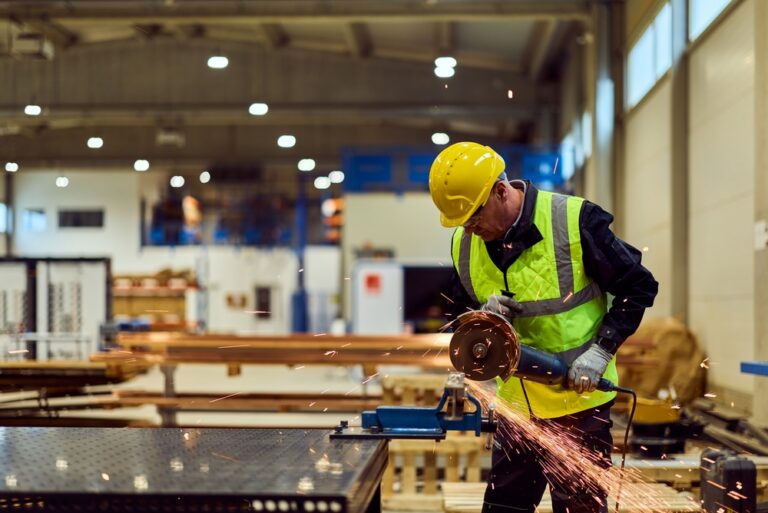 Man using an angle grinder on metal in a workshop, with sparks flying