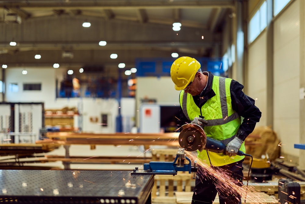 Man using an angle grinder on metal in a workshop, with sparks flying